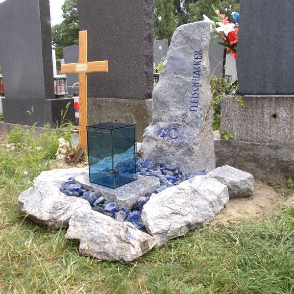 Zechmeister - Urnengrab mit bläulichem Granit und blauen Glassteinen und blauer Glaslaterne, am Grabstein ein graviertels Unendlichkeitszeichen - Wien Aspern